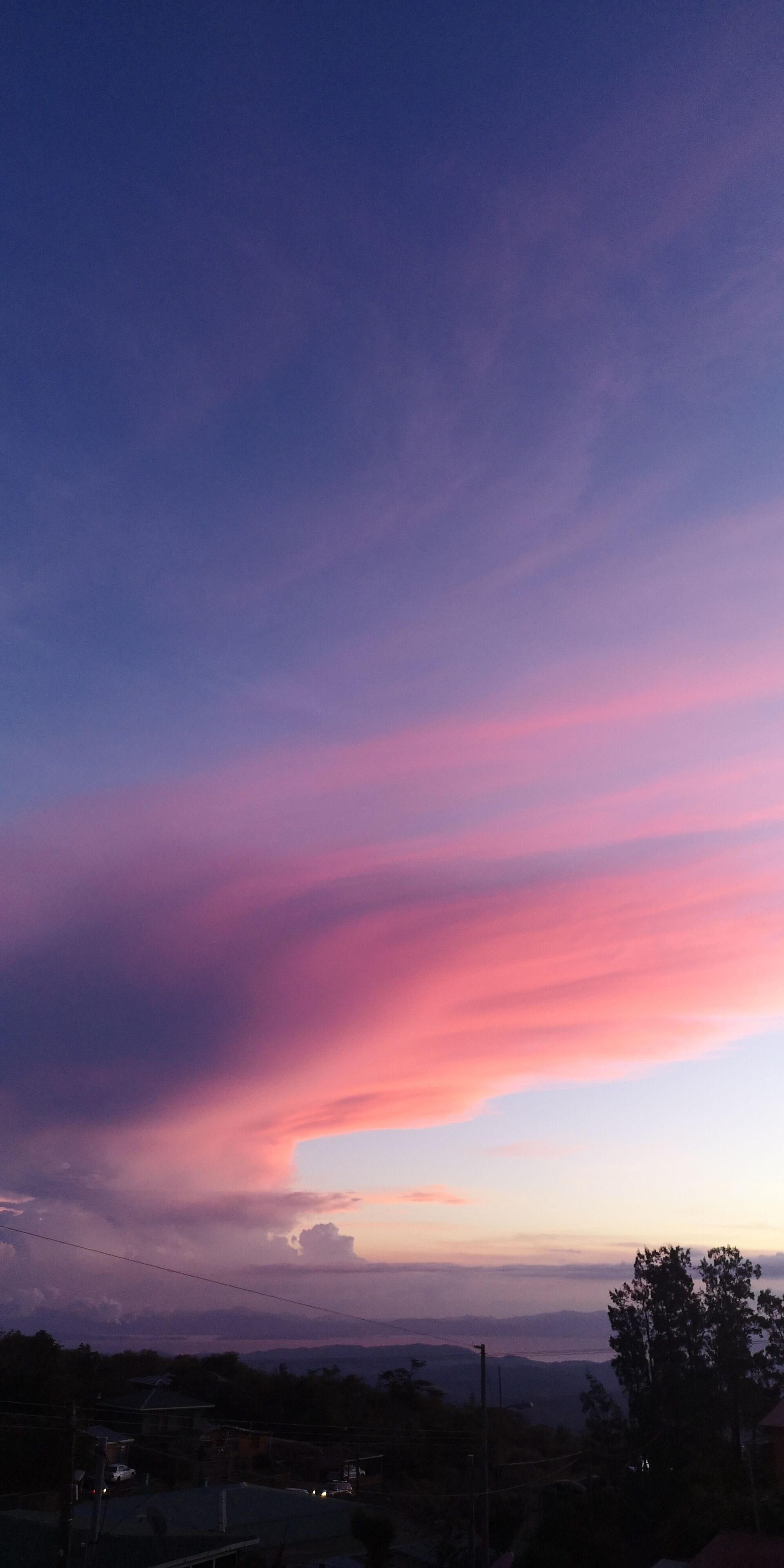 A sunset with pink and purple clouds over a residential area.
