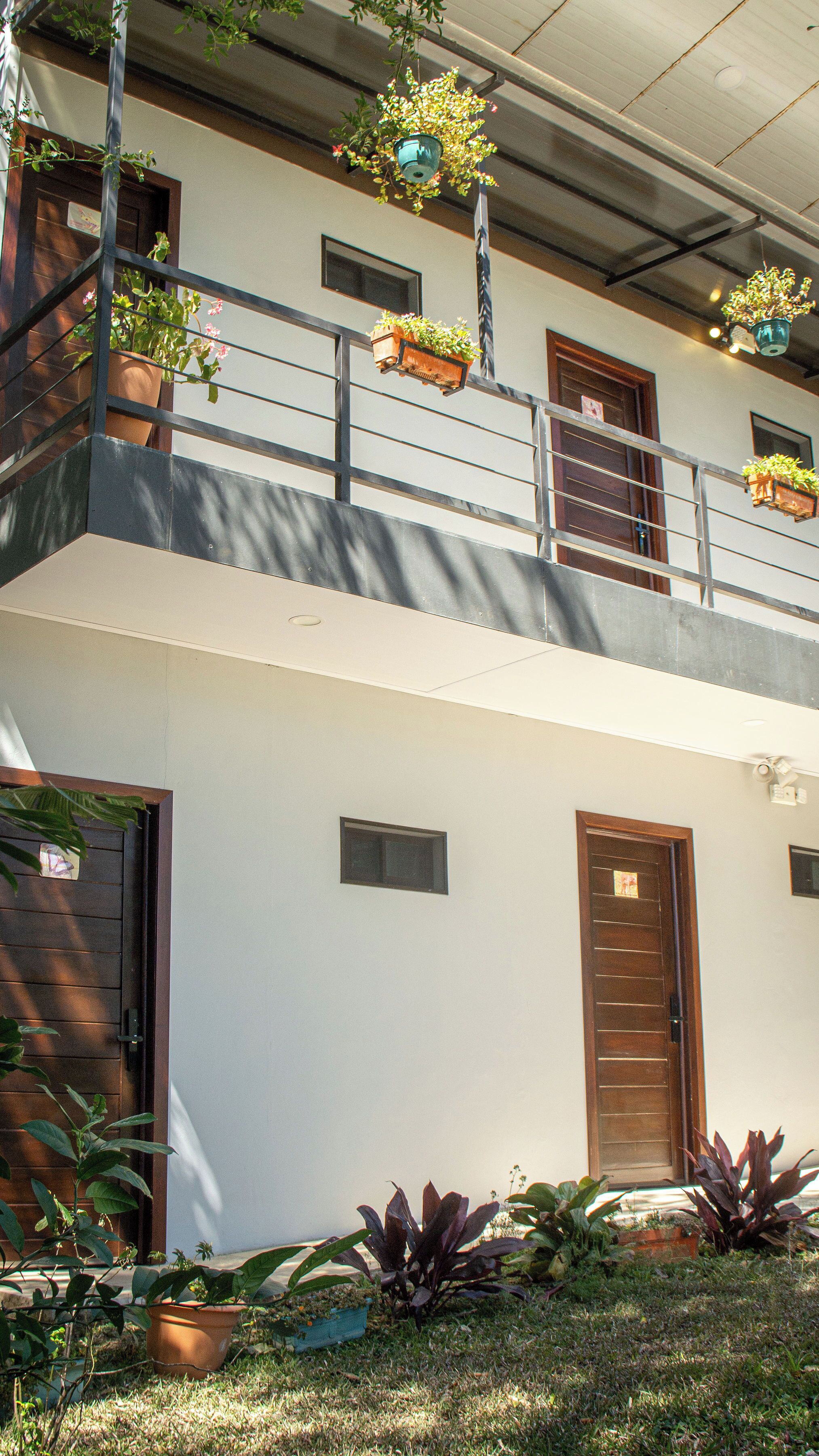 A two-story building with balconies, potted plants, and a door.