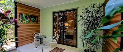 A patio area with a table and chairs, a potted plant, and a sliding glass door leading to an interior space.