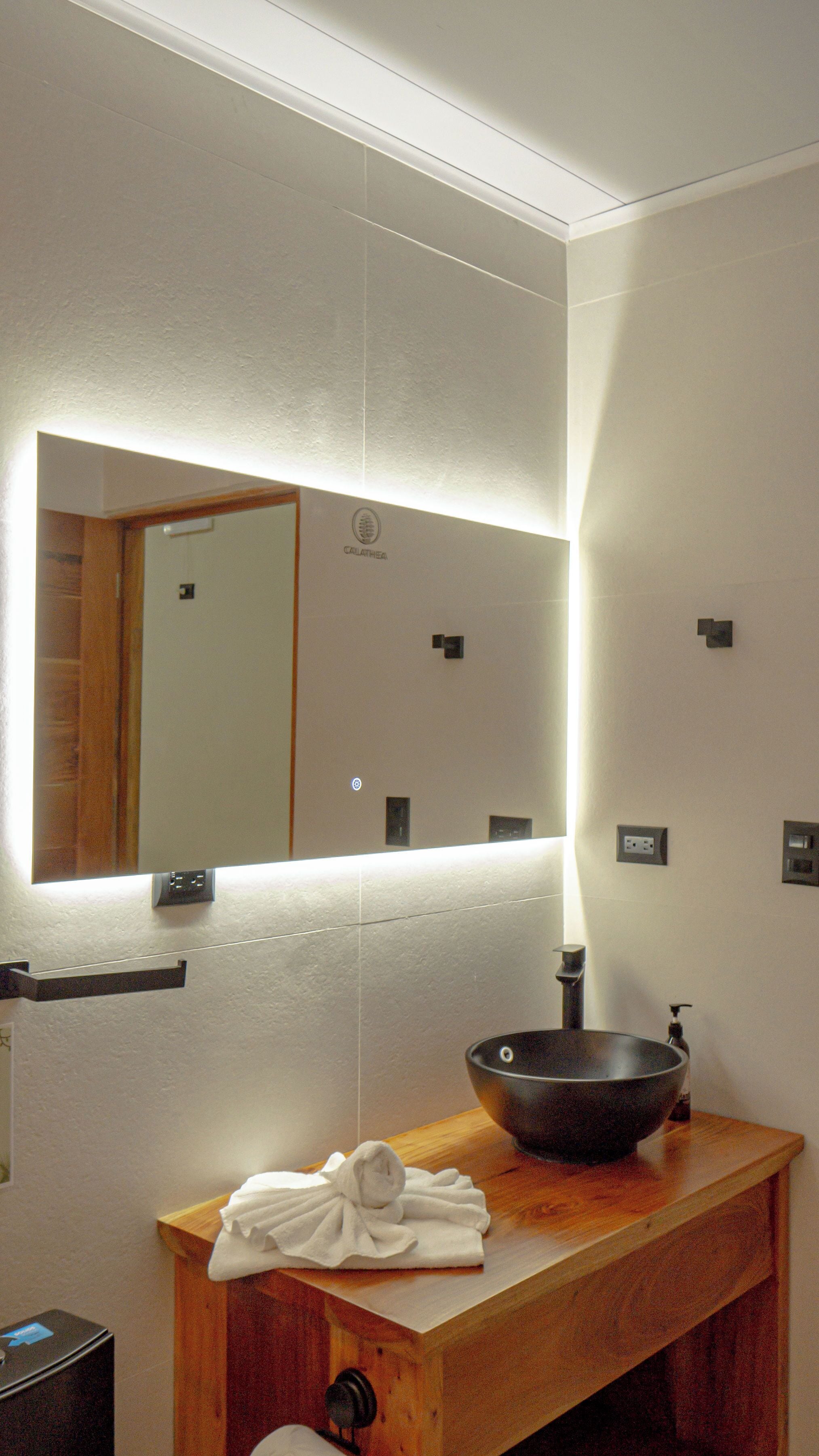 A bathroom with a wooden vanity, a black basin, a mirror, and a towel rack.