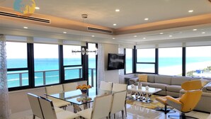 Un salón espacioso con una gran mesa de vidrio, asientos cómodos y vistas al océano.