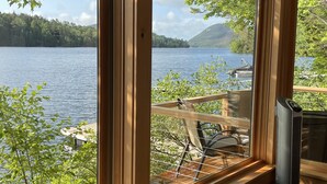 A room with large windows overlooking a lake, a dock, and a mountain.