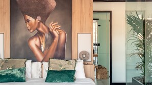 A modern bedroom with a large bed, a mural on the wall, and a glass partition with a plant. - ChezmoiHomes Luxury Alhambra Penthouse Collection Alhambra (Granada)