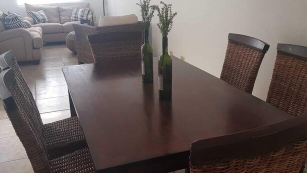 A dining area with a long wooden table, wicker chairs, and two hanging pendant lights. - Vista Hermosa -libre de humo- (Ensenada)