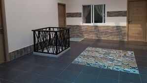 Un passadís amb terra de rajola, barana metàl·lica i un rug elegant.