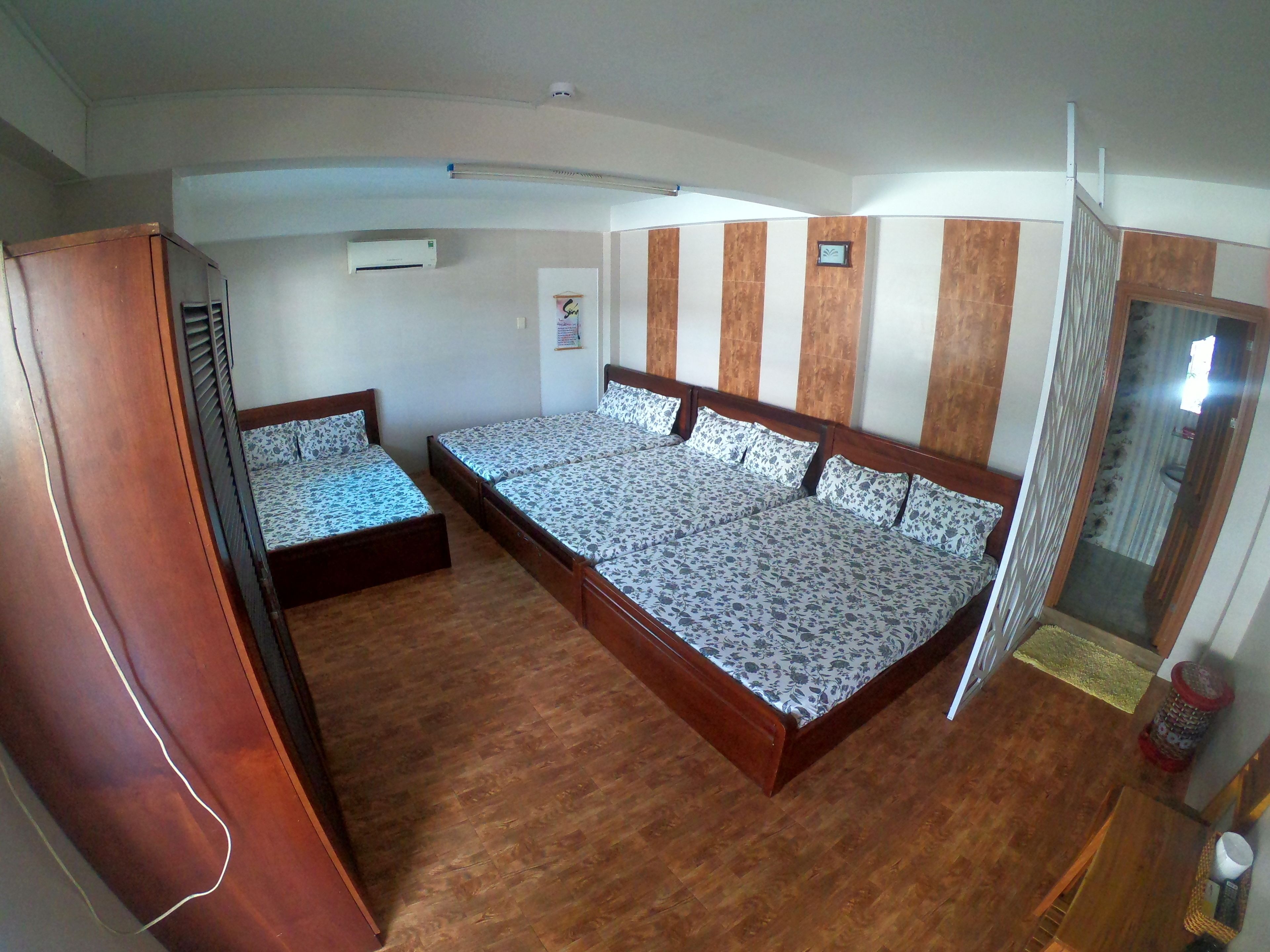 A bedroom with two beds, wooden flooring, a wardrobe, and a ceiling fan.