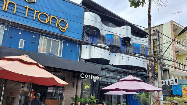 Una cafeteria amb terrassa i un edifici blau amb un rètol que diu "Coffee".