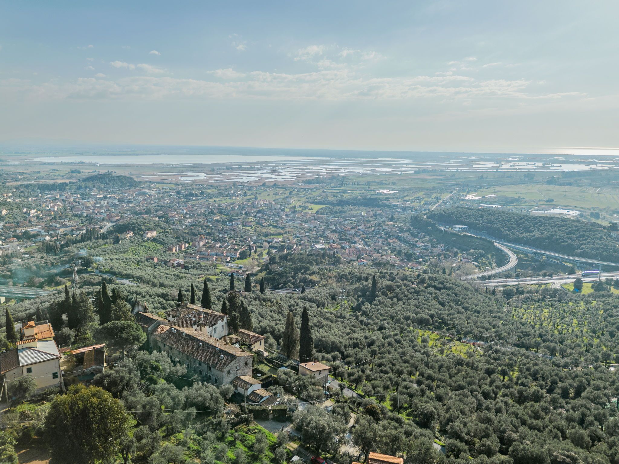 Une vue panoramique d’une ville où se côtoient des bâtiments résidentiels et commerciaux, le tout entouré de verdure et bordé par une rivière.