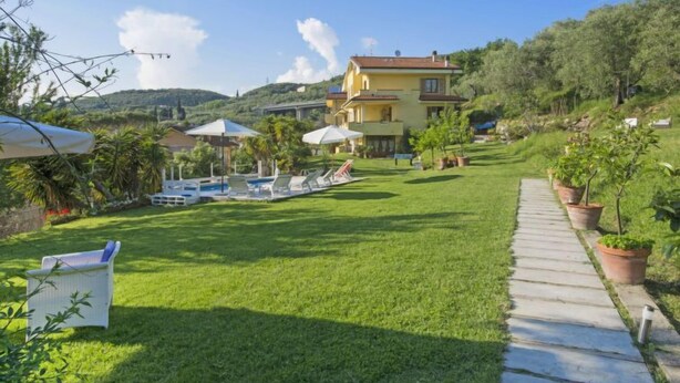 Un hotel con piscina, sillas de descanso y césped.