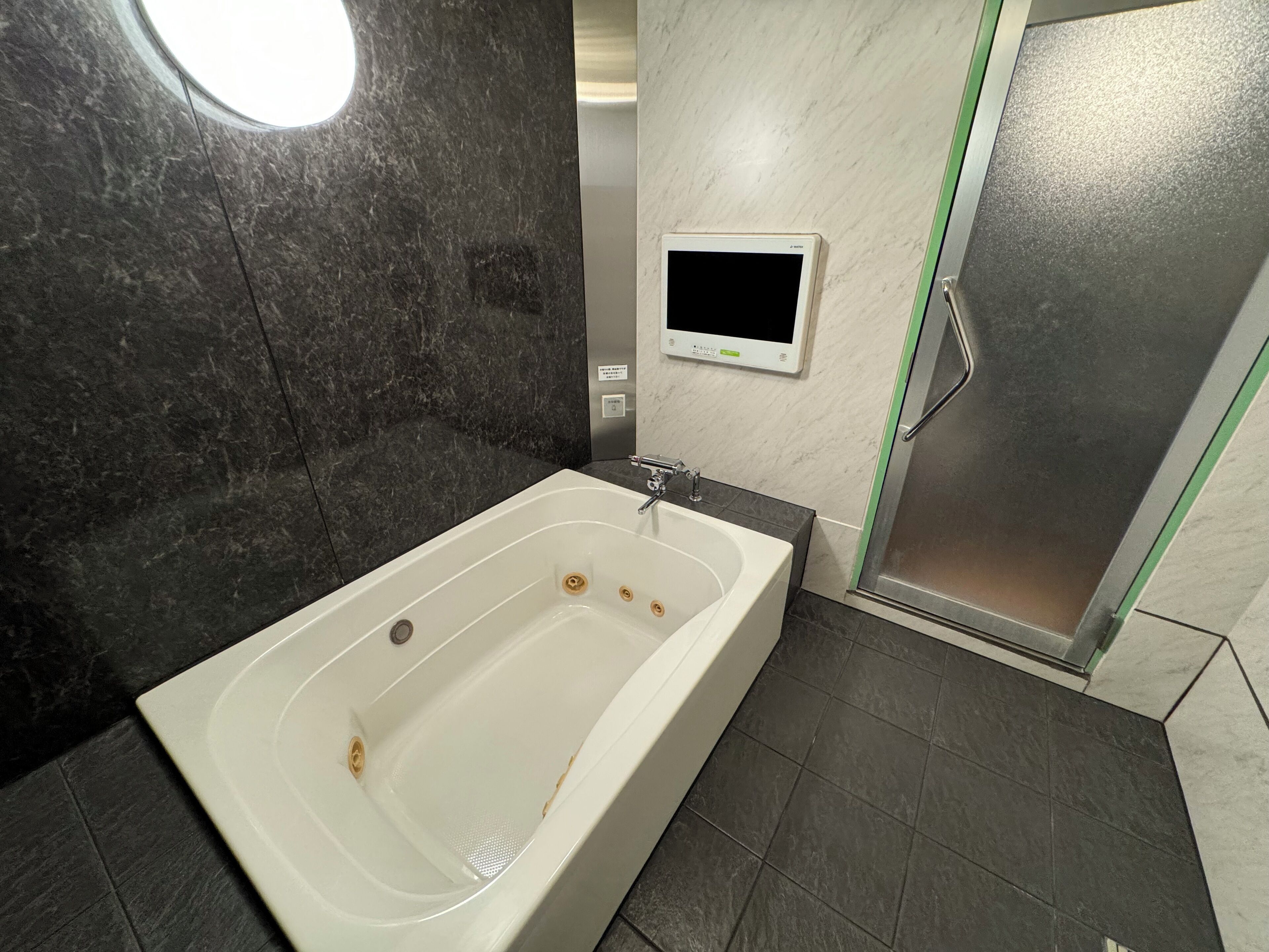 A modern bathroom with a large bathtub, a built-in toilet, and a shower area.