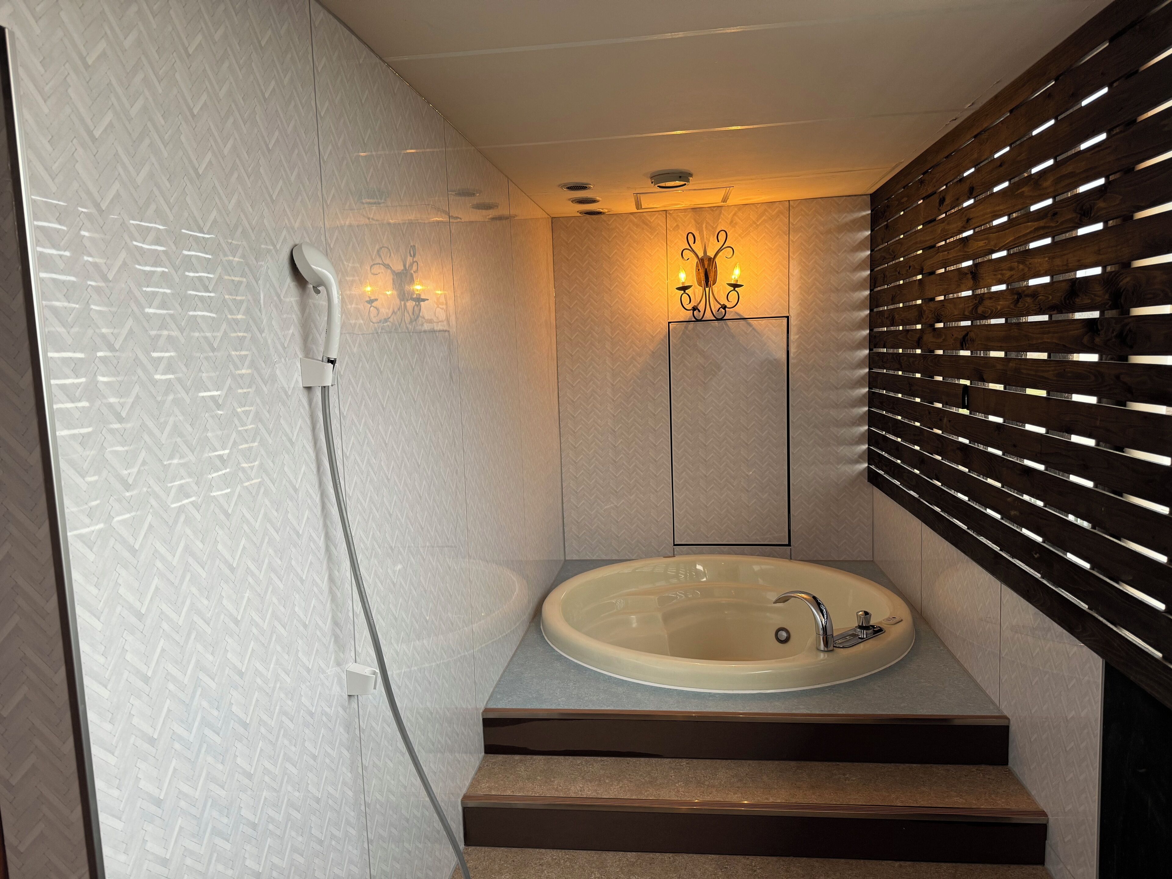 A modern bathroom with a freestanding bathtub, a showerhead, and a wall-mounted light fixture.