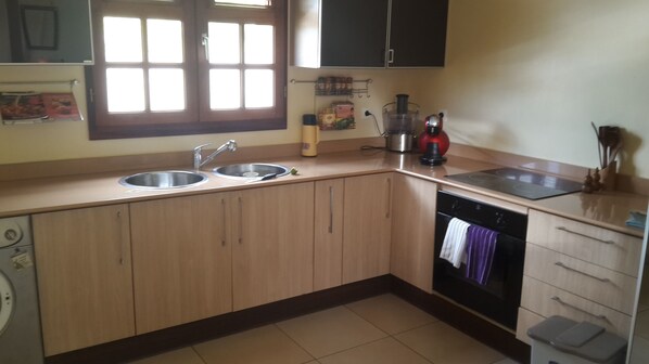 A kitchen with wooden cabinets, a double sink, a stove, and a dishwasher. - Wooden chalet, sea view (SAINT -CLAUDE)
