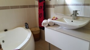 A bathroom with a bathtub, a sink, and a toilet. - Wooden chalet, sea view (SAINT -CLAUDE)