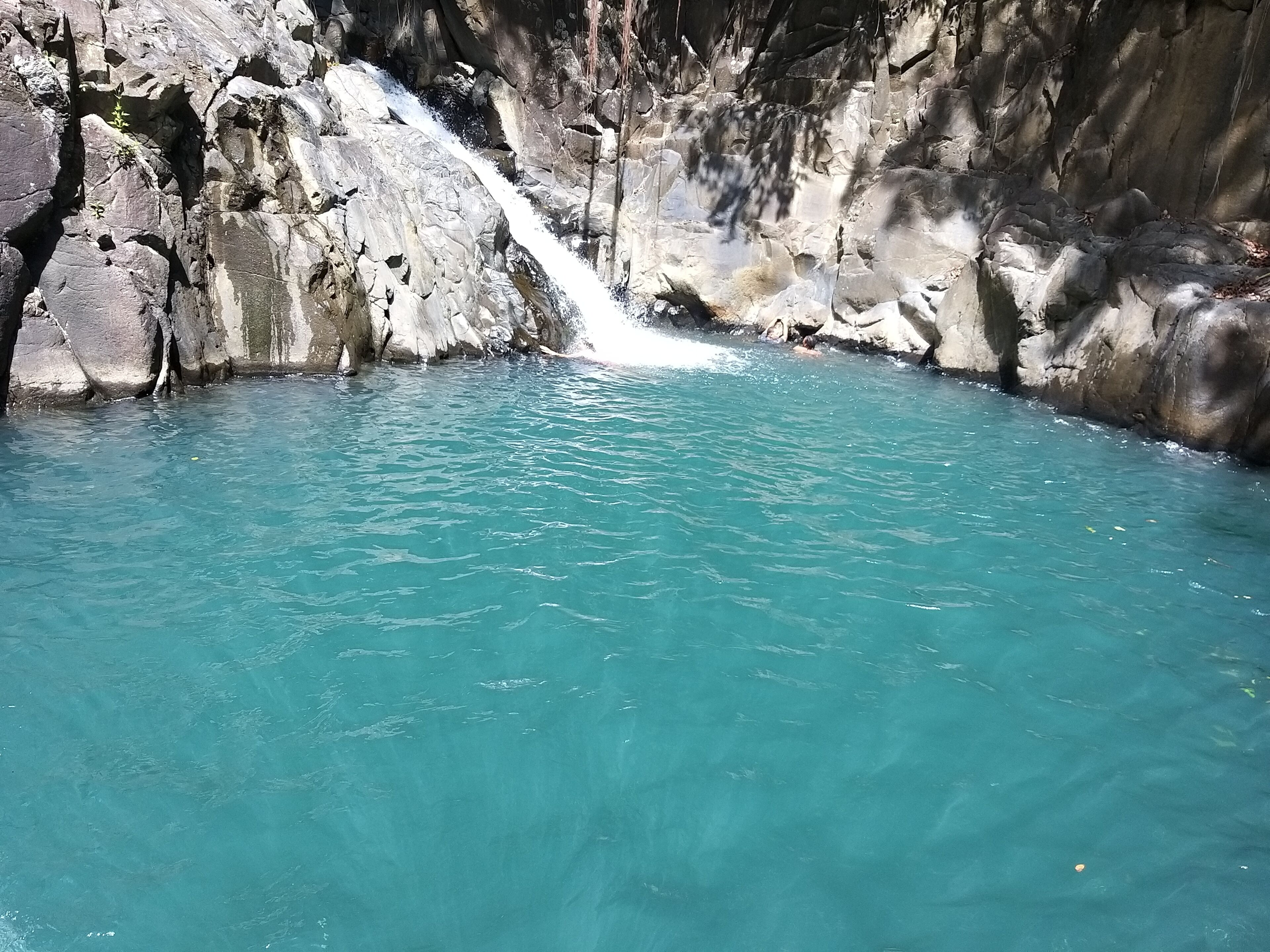 Une piscine naturelle à l’eau turquoise et limpide, entourée de falaises rocheuses.