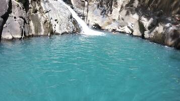 Une piscine naturelle à l’eau turquoise et limpide, entourée de falaises rocheuses.
