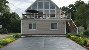 A two-story building with a balcony, a covered outdoor seating area, and a driveway.