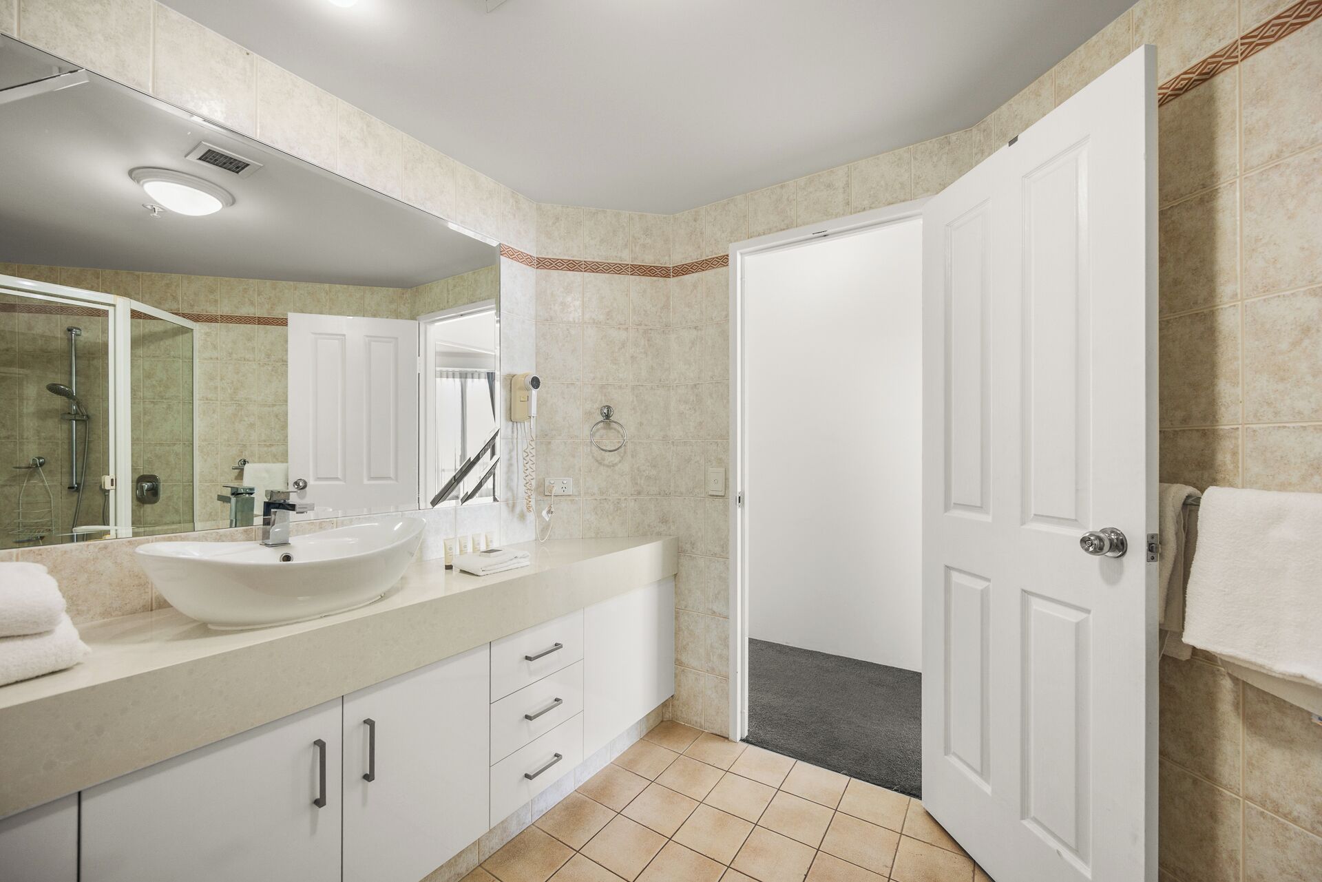 A modern bathroom with a large sink, mirror, and shower.