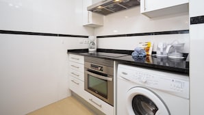 A modern kitchen with white cabinets, a black countertop, a built-in oven, a dishwasher, and a coffee maker. - Beautiful and cheerful holiday house in Javea, Costa Blanca, Spain  with communal pool for 2 persons (Javea)