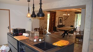 A modern kitchen with a central island, built-in appliances, and a dining area with a table and chairs.
