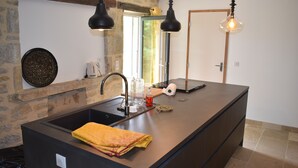 A kitchen with a large island, a sink, and hanging pendant lights.
