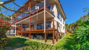 Et moderne hus med to etager, en balkon, store vinduer og en velplejet have.