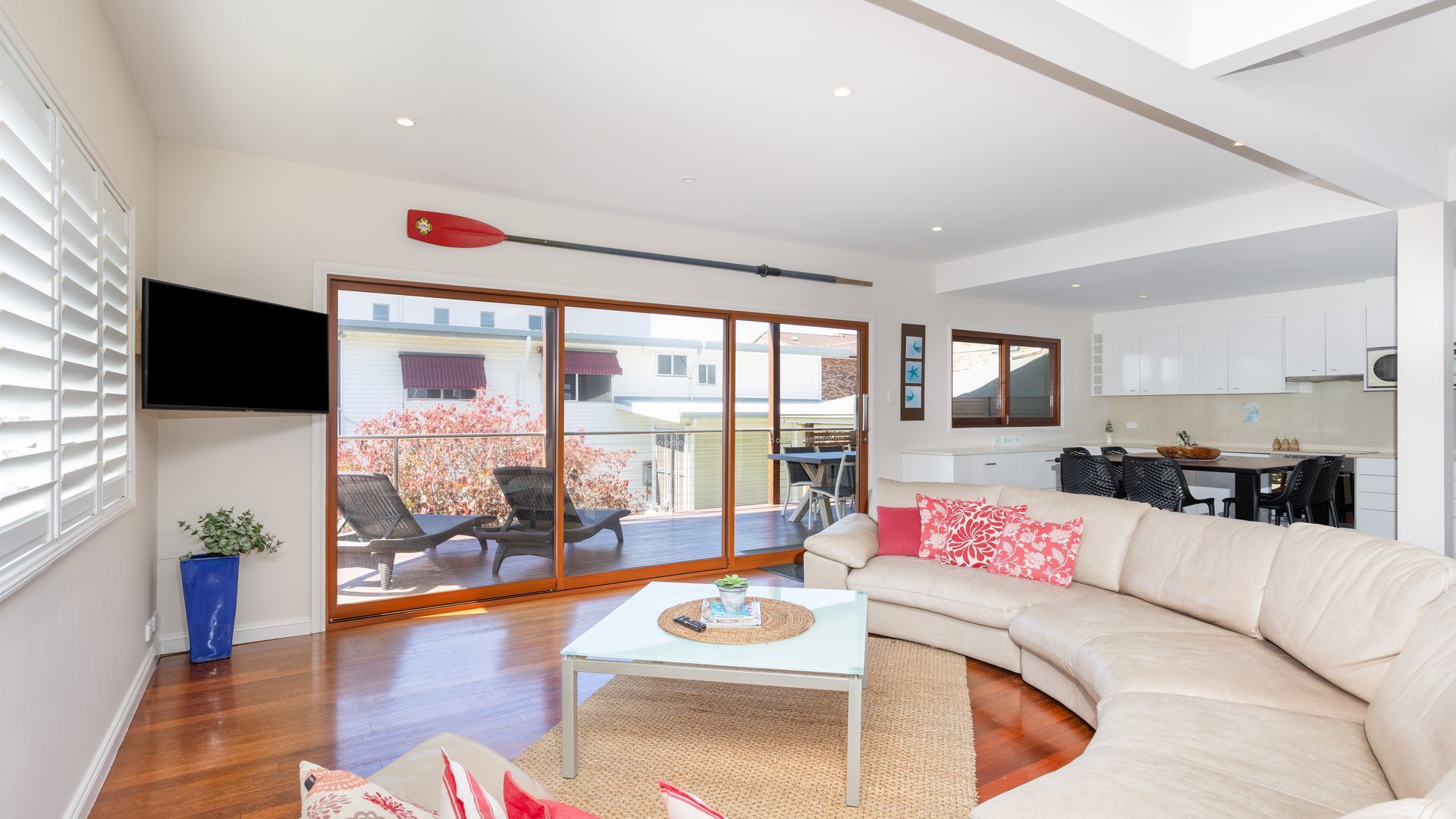 A modern living room with a sofa, a coffee table, and a dining area visible through a sliding glass door.