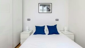 Un dormitori minimalista amb un llit gran, dues taules de nit i un quadre al mur.