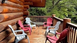 Una terraza de madera con una mesa y sillas, rodeada por barandilla de madera.