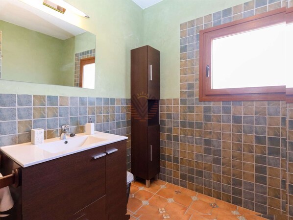 A bathroom with a sink, mirror, cabinet, and tiled walls. - Casa Fina, Holiday house in Felanitx, Mallorca (Felanitx)