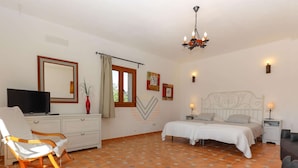 A bedroom with a bed, a chair, a television, a dresser, and a window with curtains. - Casa Fina, Holiday house in Felanitx, Mallorca (Felanitx)