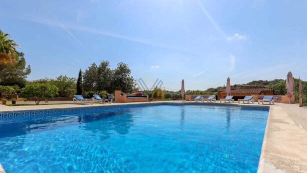A clear blue swimming pool with lounge chairs and umbrellas, surrounded by greenery and buildings. - Casa Fina, Holiday house in Felanitx, Mallorca (Felanitx)