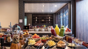 A buffet with various food items and beverages, a kitchen area with utensils, and a view of the room's interior.