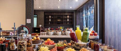 Ein Buffet mit verschiedenen Speisen und Getränken, eine Küchenzeile mit Kochutensilien sowie Blick ins Zimmerinnere.