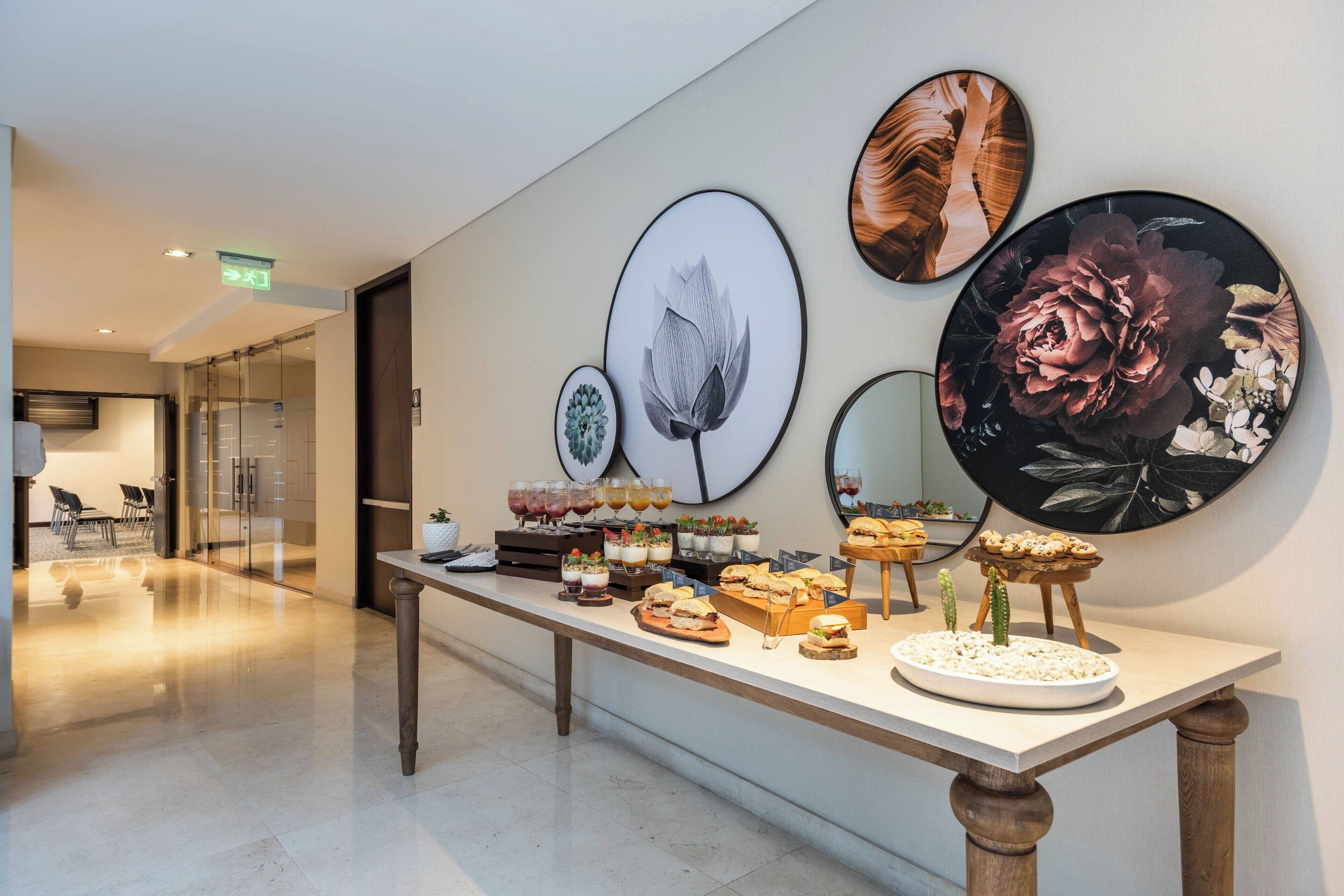 Ein reichhaltiges Buffet mit verschiedenen Speisen und Getränken, vor einer Wand mit gerahmten Blumenbildern.
