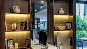 A modern workspace with a desk, chairs, and shelves with decorative items.