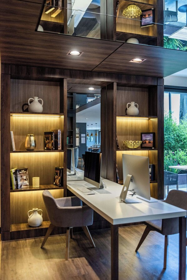 A modern workspace with a desk, chairs, and shelves with decorative items. - AC Hotel by Marriott Bogota Zona T (Bogotá)