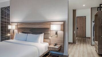 Ein modernes Hotelzimmer mit einem großen Bett, zwei Nachttischen mit Lampen, einem Holz-Kopfteil und einem Holzschrank.