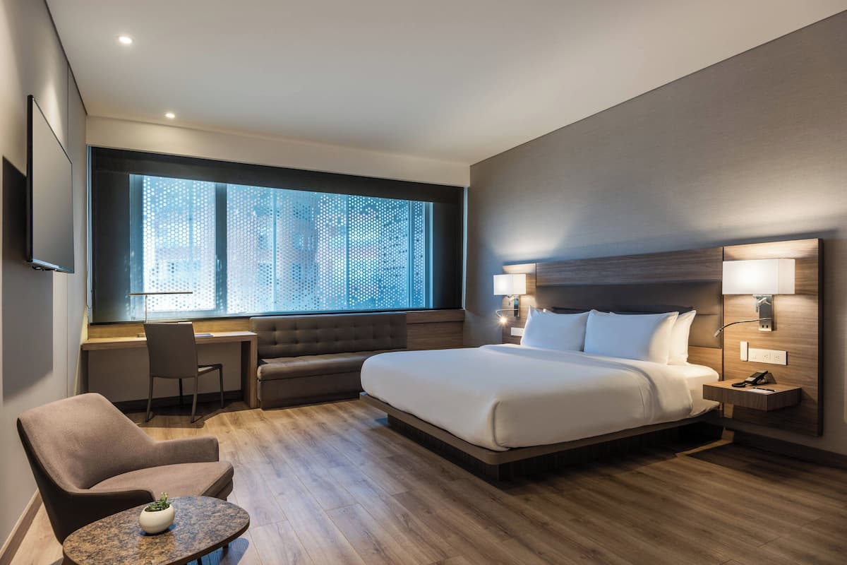 Una habitación de hotel moderna con una cama grande, un escritorio, una silla y una pequeña mesa.
