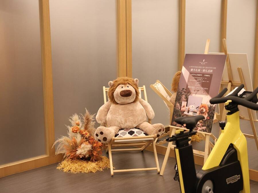A room with a large stuffed animal on a chair, a yoga bike, and a poster on the wall.