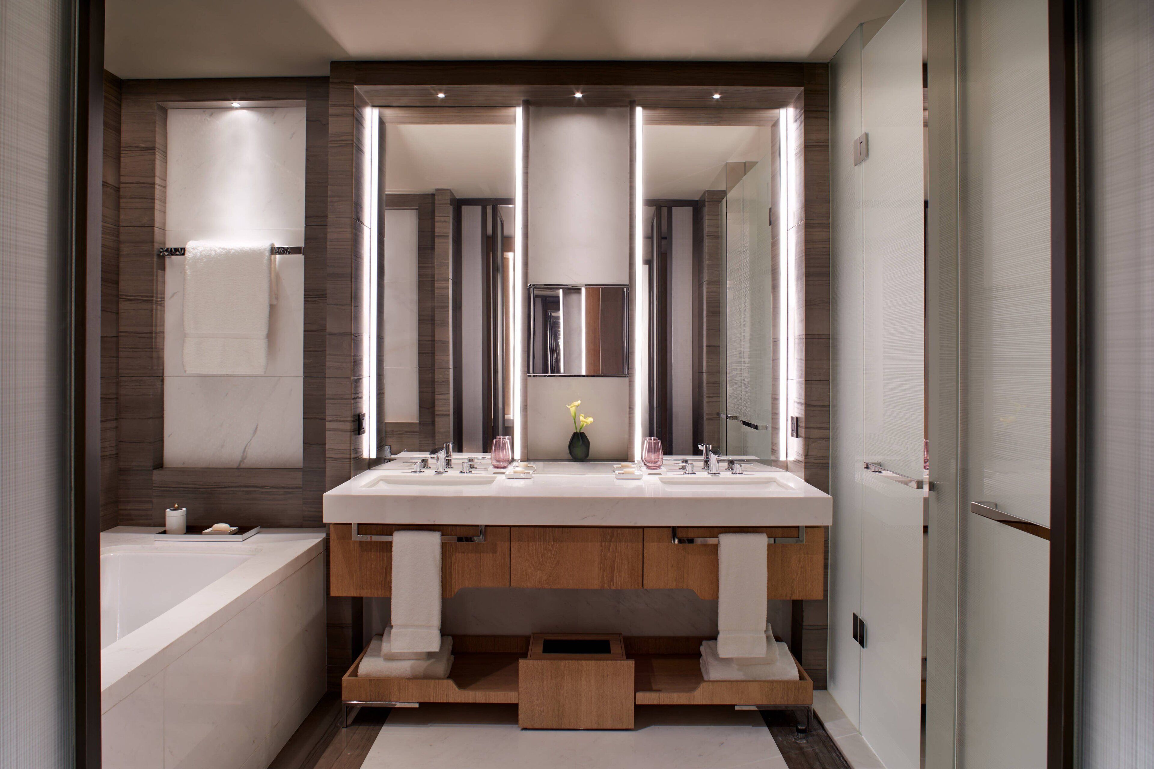 A modern bathroom with a double sink vanity, a large mirror, and a bathtub.