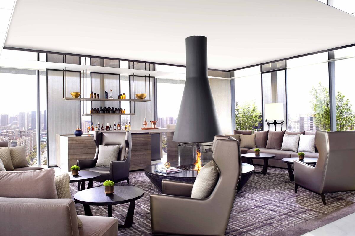 A modern lounge with sofas, tables, and a fireplace.