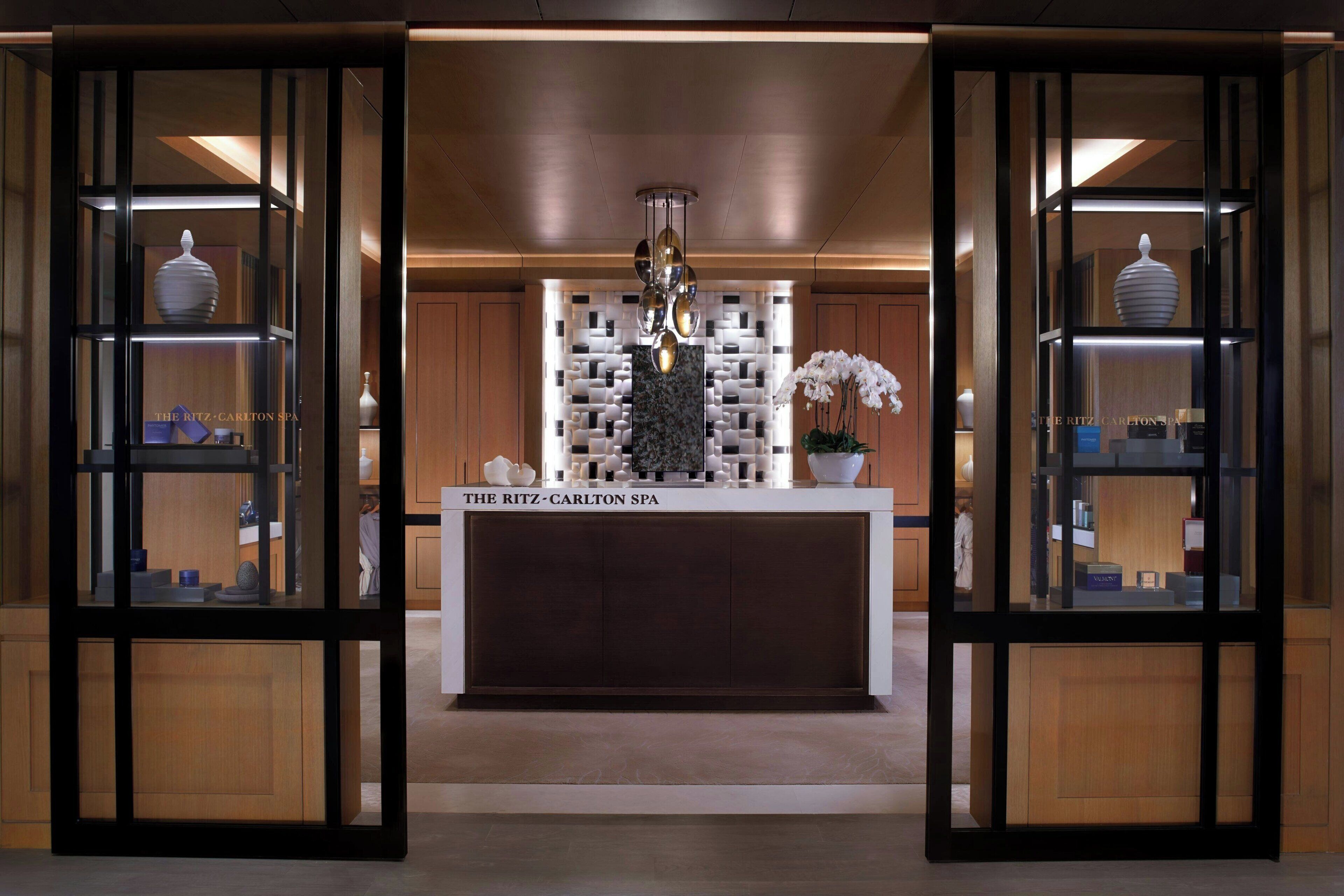 A reception area with a central counter, wooden cabinets, and glass display cases containing various items.