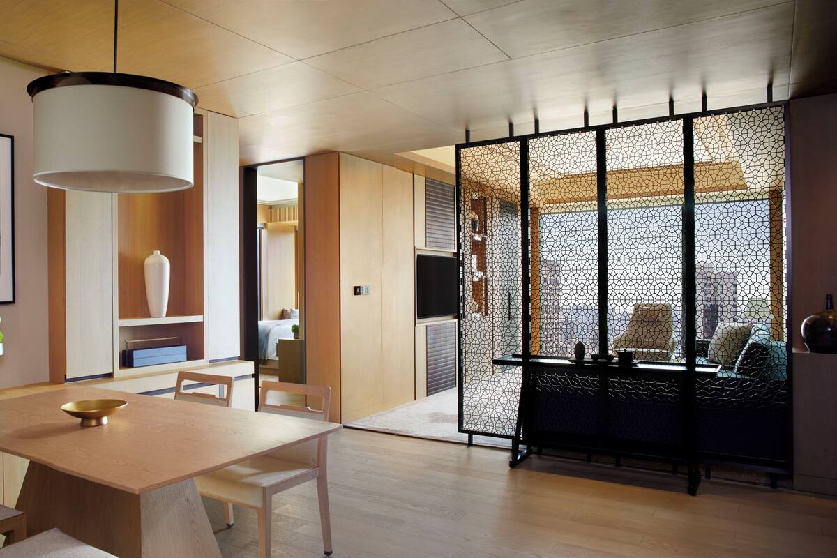 A modern interior with a dining area, a large vase, and a view through a patterned screen.
