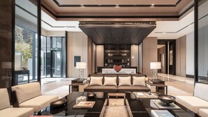 A modern living room with a sofa, coffee table, and lamps. There is a reception desk in the background. - The Ritz-Carlton, Xi'an (Xi'an)