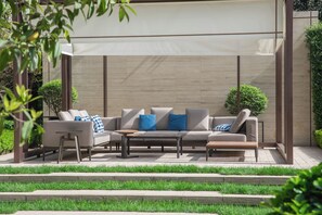 Un espace extérieur moderne aménagé avec un canapé, deux petites tables d’appoint et une table basse.