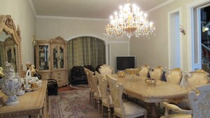 Une salle à manger élégante, avec une grande table, des chaises richement décorées, un lustre et un grand miroir.