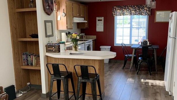 A kitchen with wooden cabinets, a white countertop, and a dining area with a table and chairs. - Views, Central AC, Location and Solitude (Irwin)