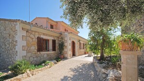 A stone building with a paved entrance, a small garden with potted plants, and a tree with fruit. - Ses Rotes - Spacious country house with private pool for 10 people in Mallorca (Campanet)