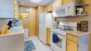 Una cocina compacta con estufa a gas, microondas y cafetera.