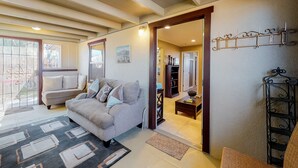 Una sala de estar con un sofá, una mesa de centro y una estantería. Hay una puerta que da a otra habitación.